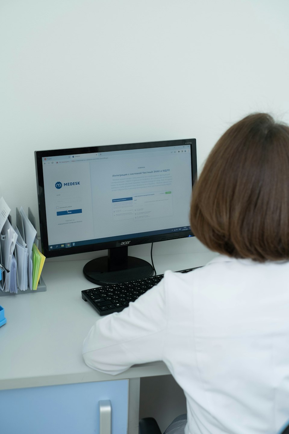 Zdravotník používá počítačový software u čistého stolu.